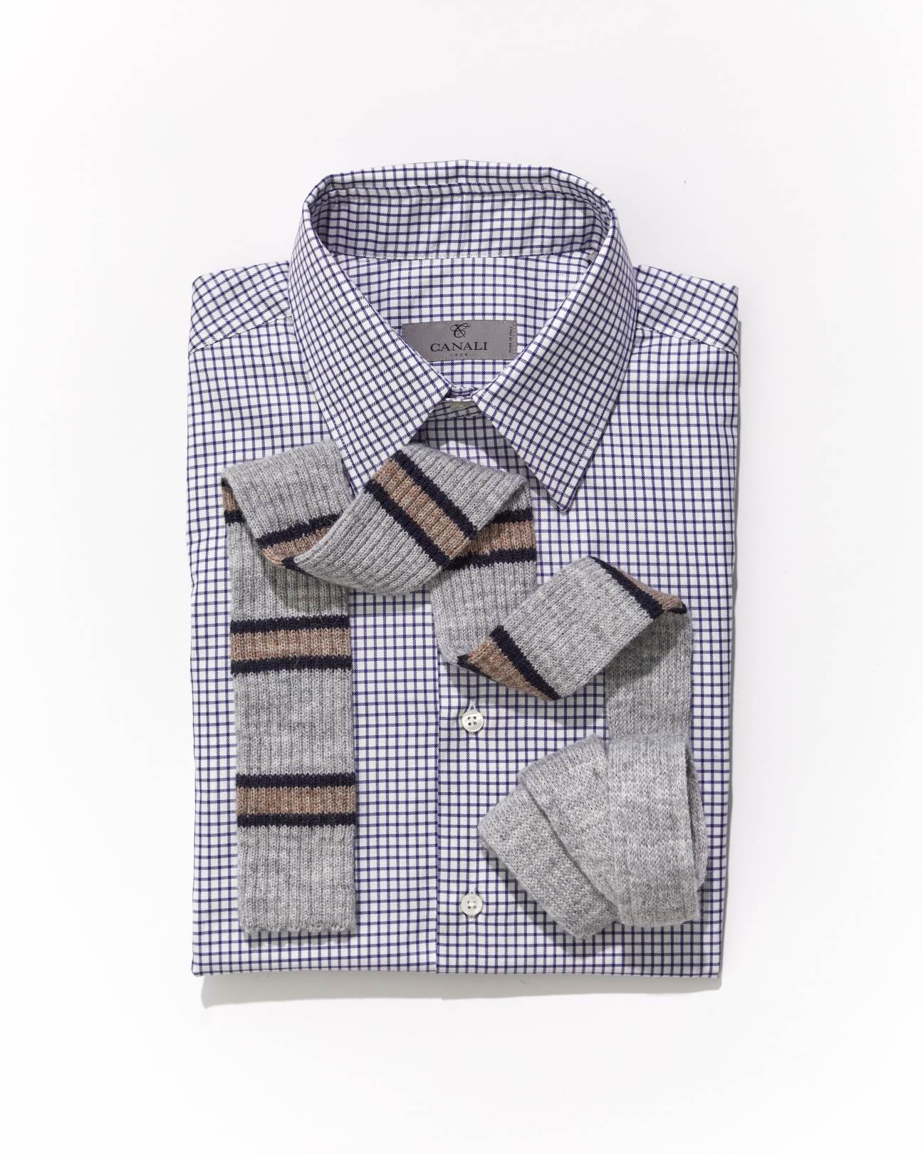 Striped knit tie draped over folded blue and white checkered dress shirt