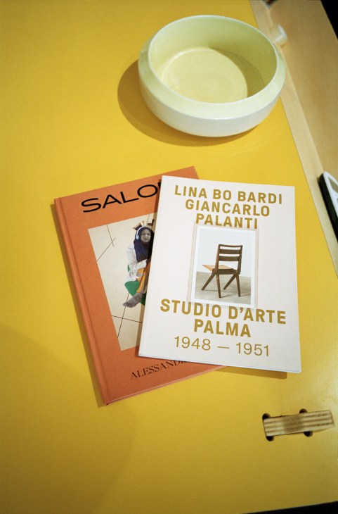 Design books and a white ceramic bowl arranged on a yellow surface.