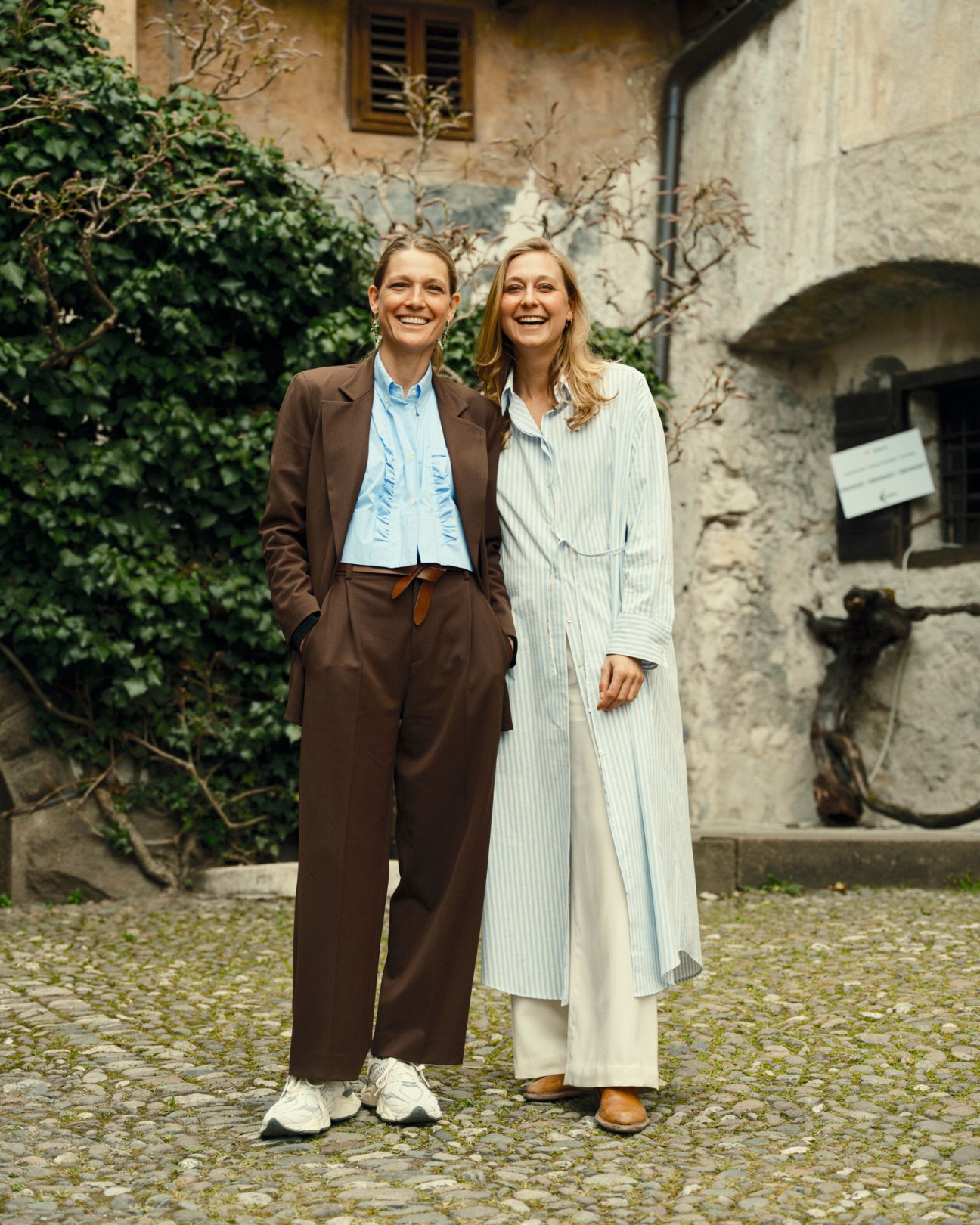 Anna and Helena Lageder standing together smiling in a courtyard at their family winery