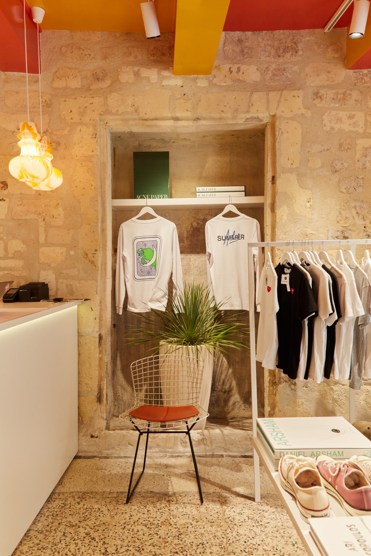 Bright retail interior with stone walls, colorful ceiling, clothing displays, and modern lighting fixtures