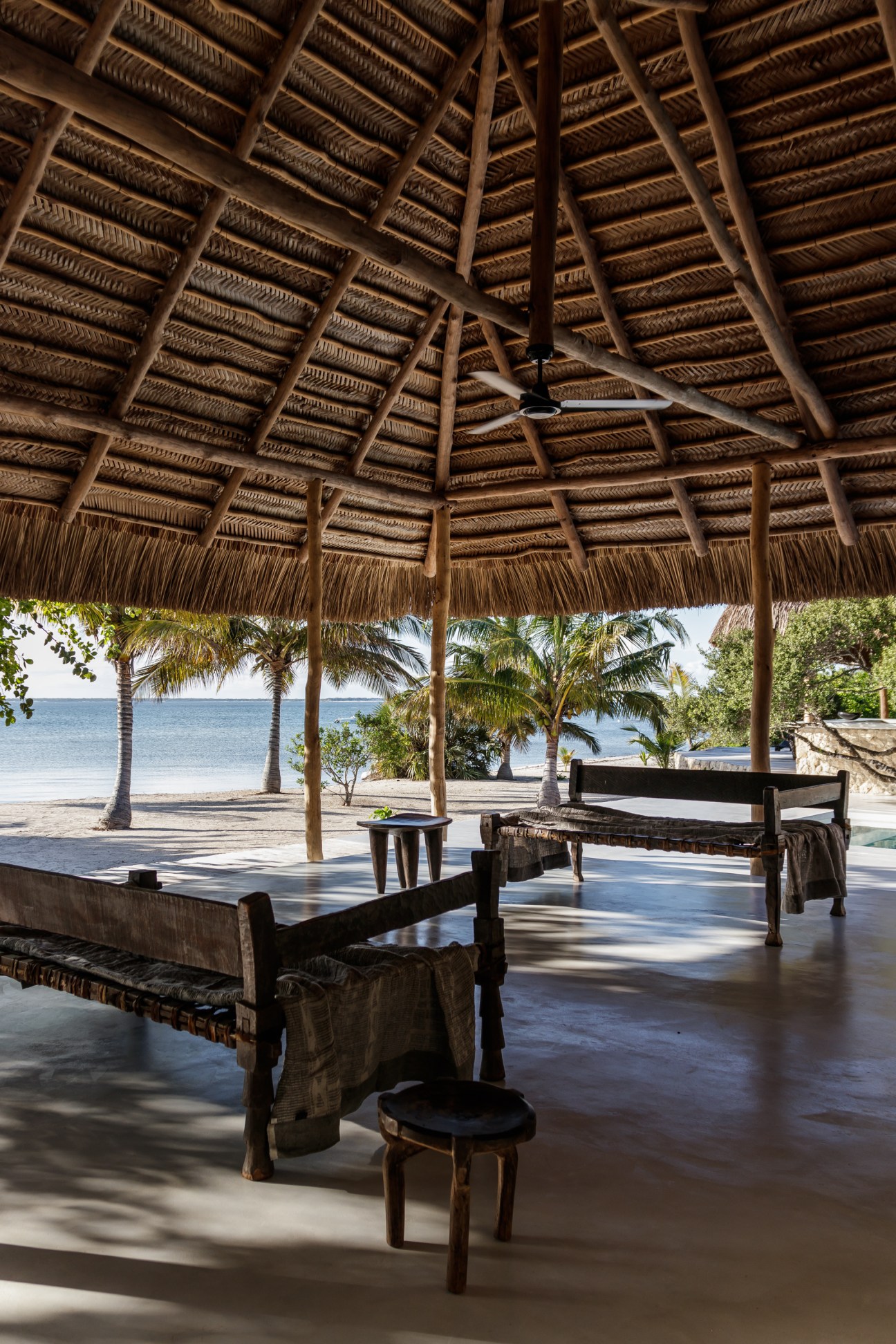Open-air dining pavilion with thatched roof, woven furniture and ocean view at Sussurro lodge