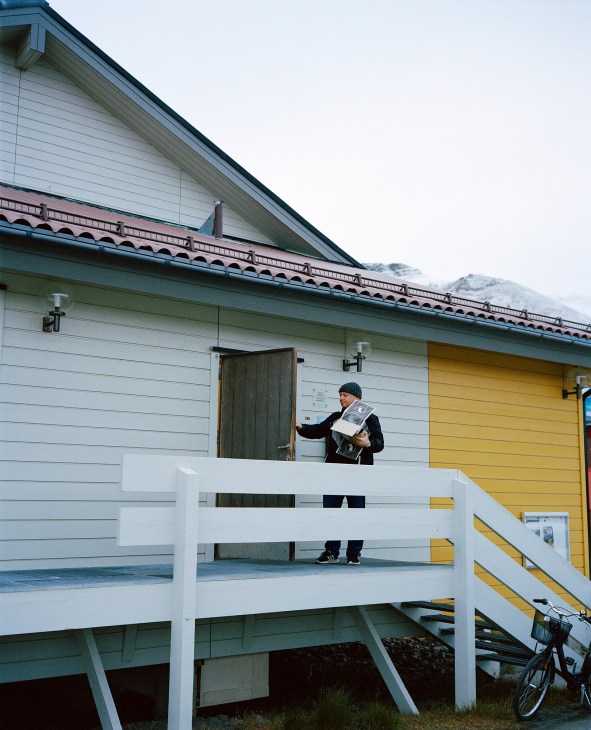 Man arriving at newspaper office building with fresh copies of Svalbardposten