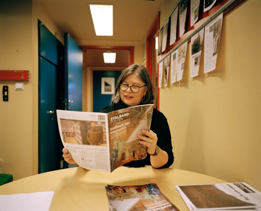 Editor conducting morning editorial review meeting with newspaper spread on desk
