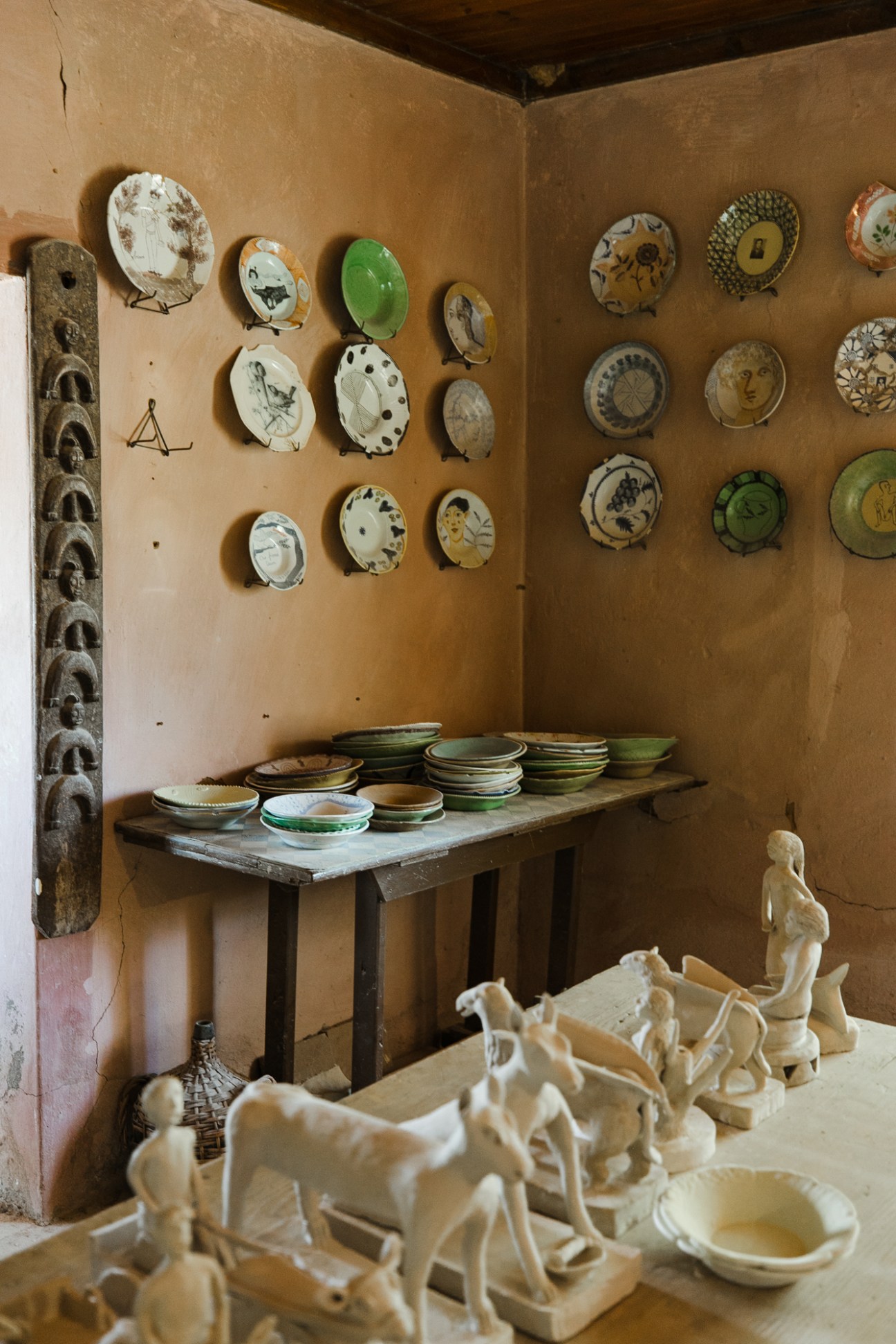 Interior of ceramics studio with decorative plates mounted on walls and ceramic figurines on table