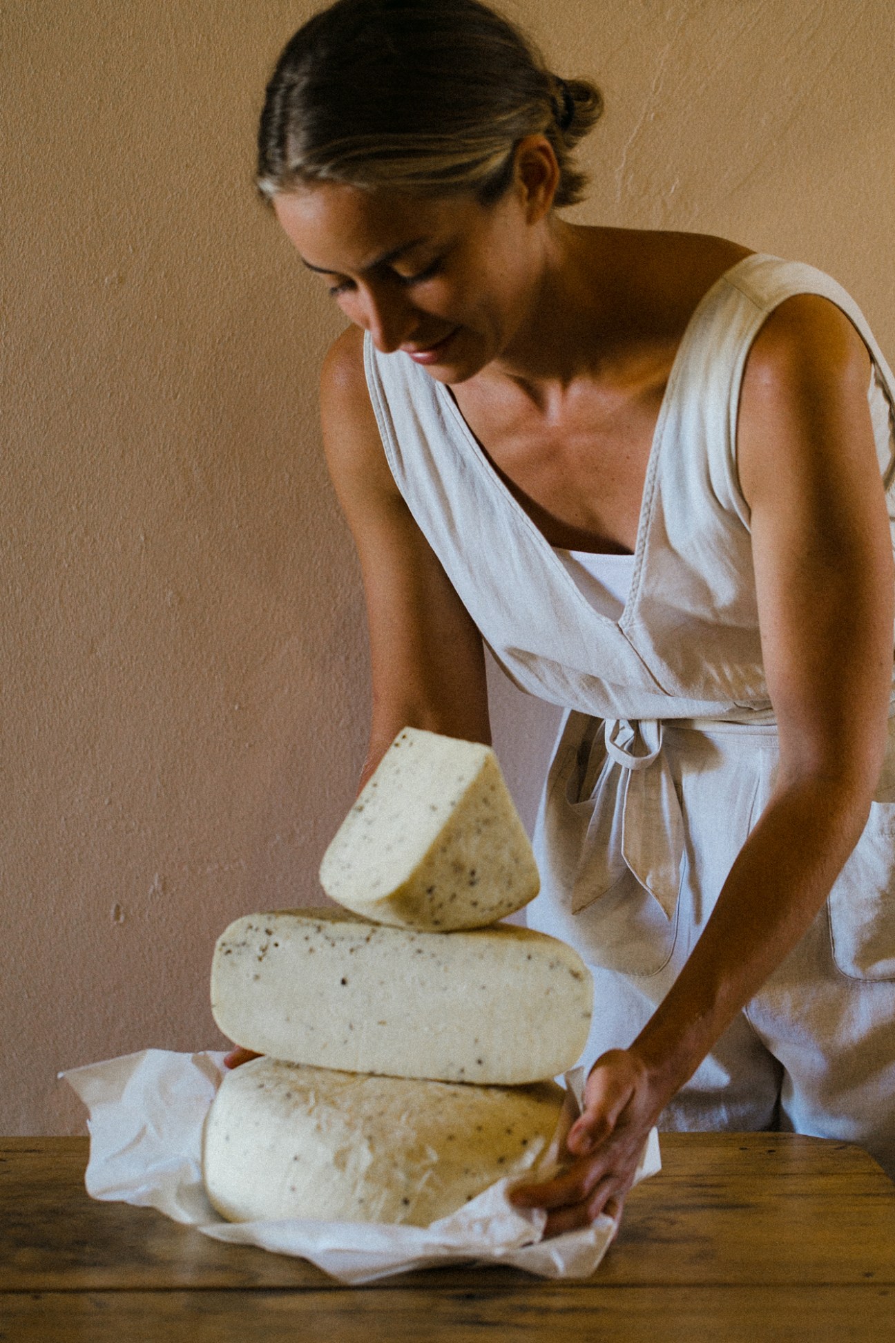 Woman in white dress arranging wheels of artisanal cheese at Gay's Guernsey Dairy