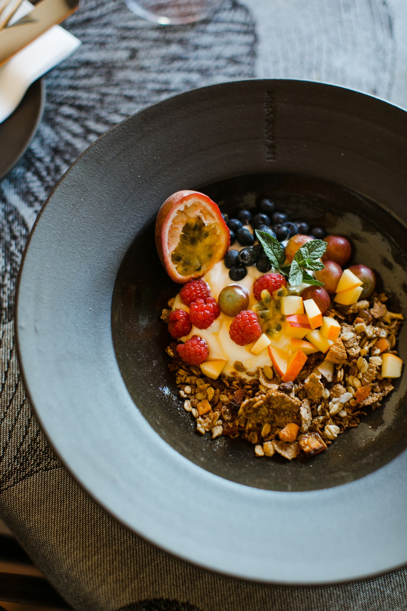 Colorful breakfast bowl with yogurt, berries, granola, passion fruit and mint at Jonkmanshof guesthouse