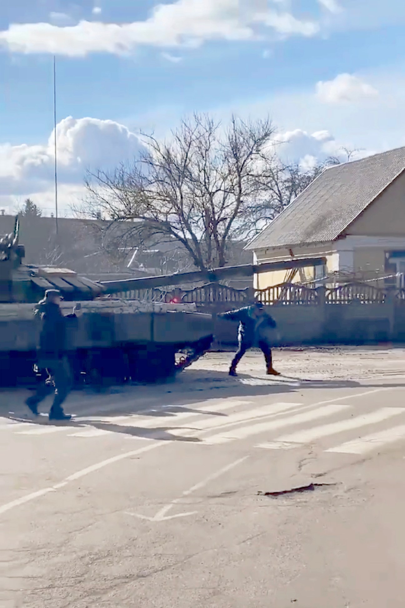 A man stands in front of advancing military tanks on a street in Ukraine during the Russian invasion.