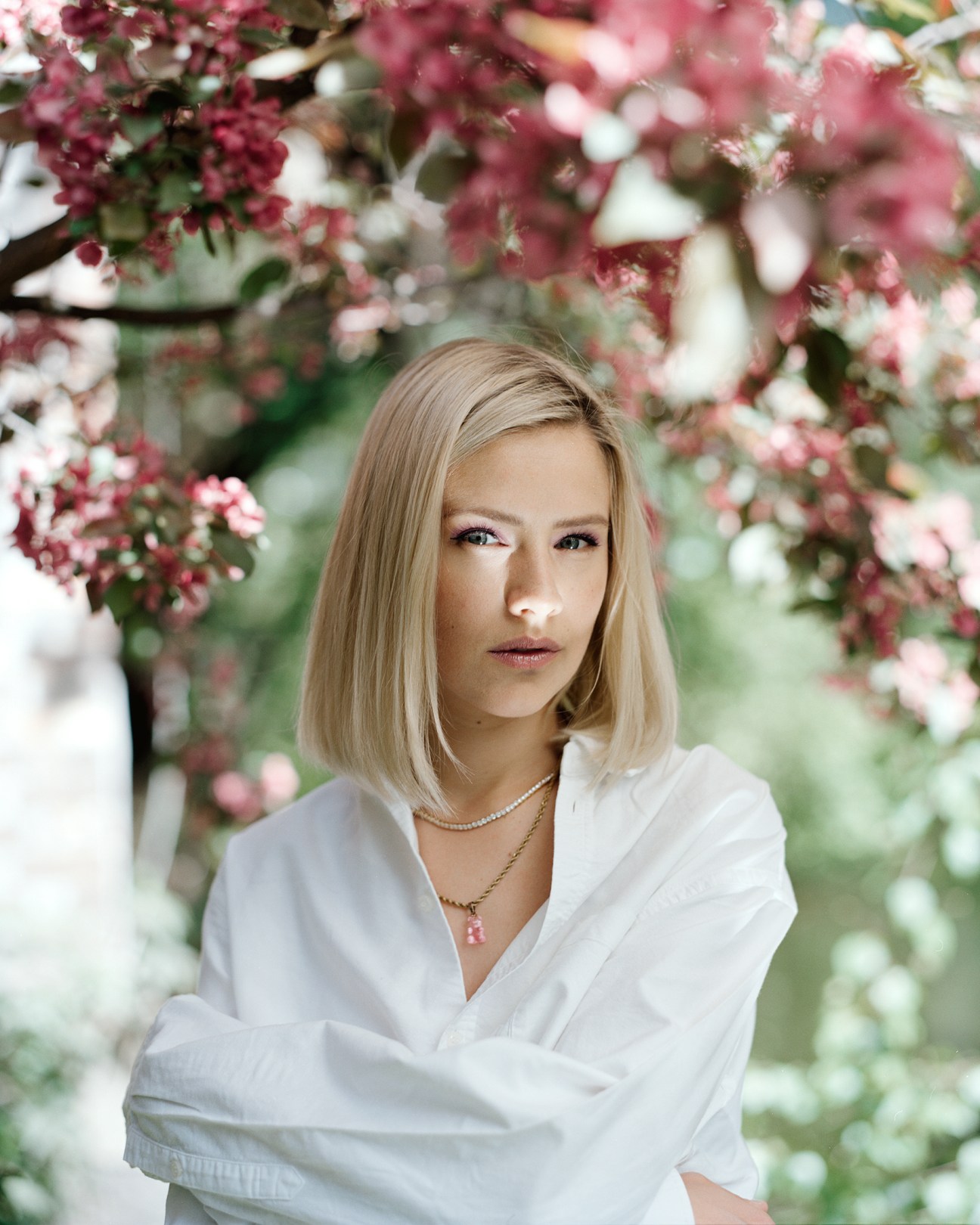 Portrait of blonde woman in white shirt under flowering tree branches