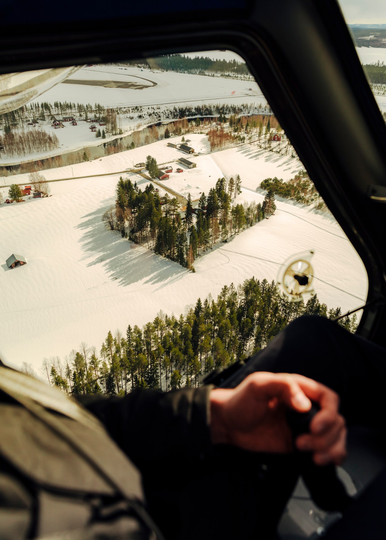 Aerial view from aircraft cockpit showing snow-covered landscape with forests and runway in Västerbotten