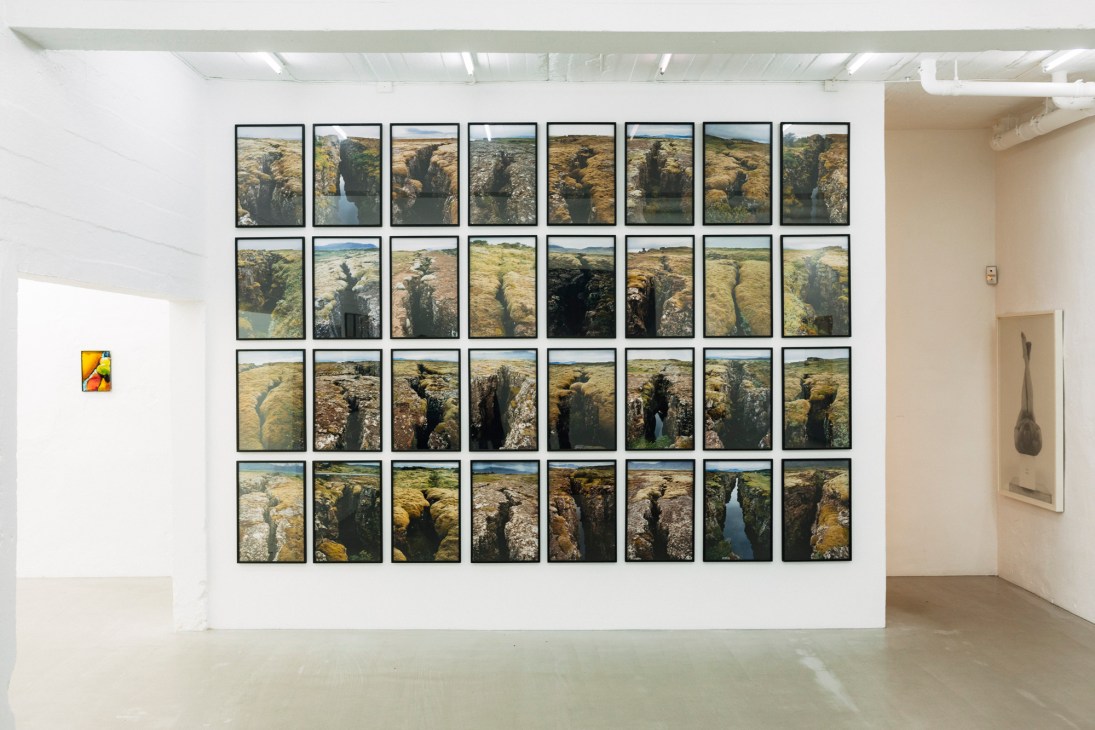 Grid of 32 framed photographs displaying aerial views of Lofoten's dramatic canyons and waterways.