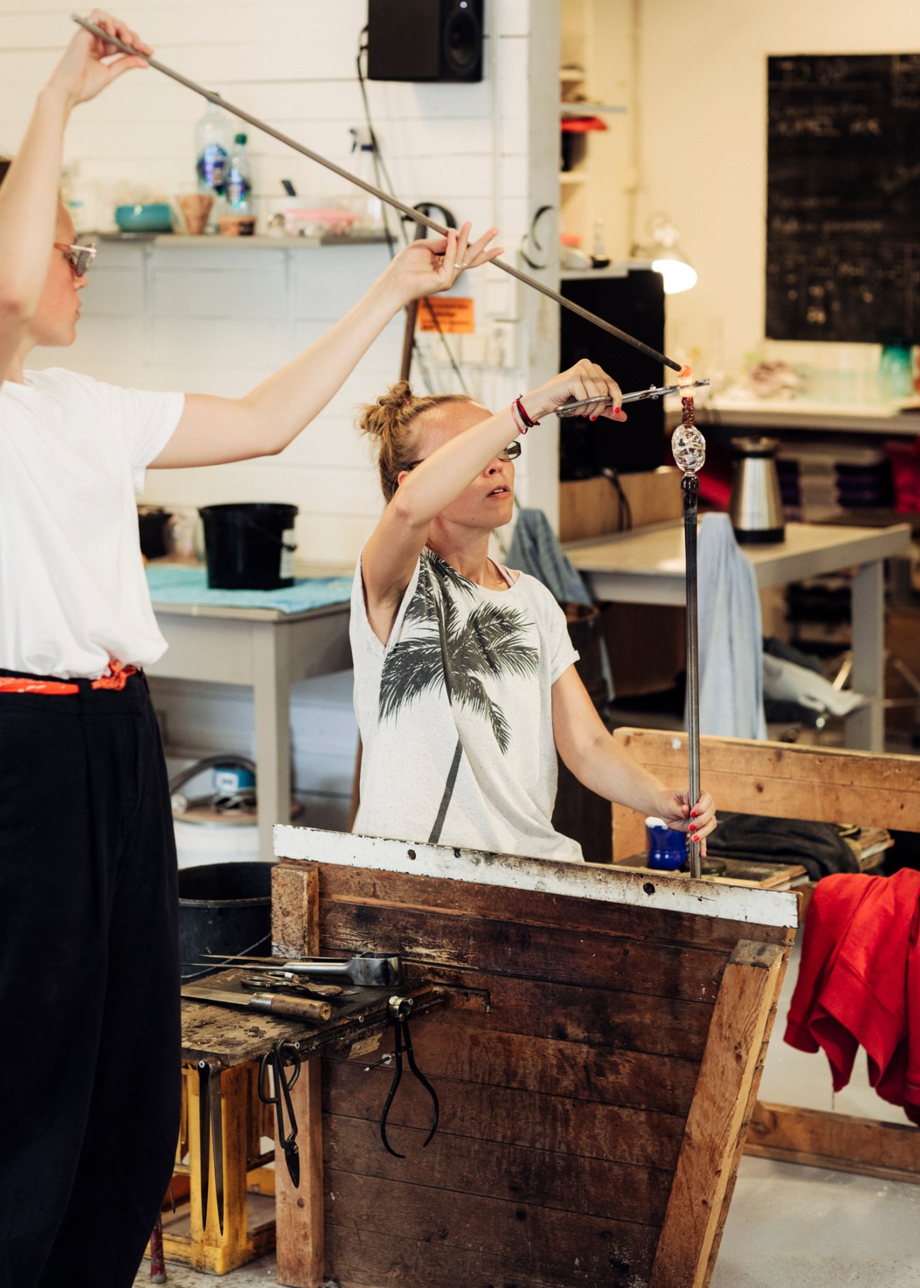 Glassblower Heidi Kristiansen working with molten glass at a furnace in a studio workshop.