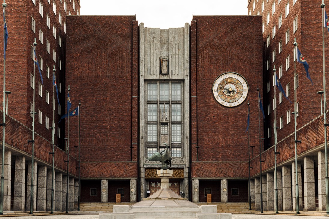Oslo City Hall entrance showing red-brown brick facade with twin towers, central clock, and symmetrical design