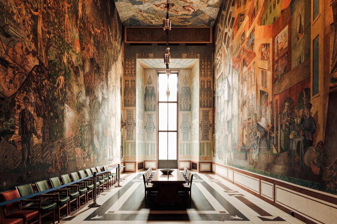 Interior view of Oslo City Hall showing large colorful murals depicting Norwegian social-democratic values on the walls