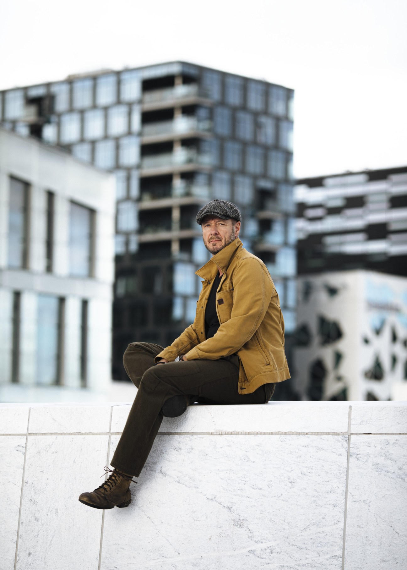 Øystein Karlsen, writer and director of Norwegian TV series Exit, sitting outdoors in mustard jacket and flat cap