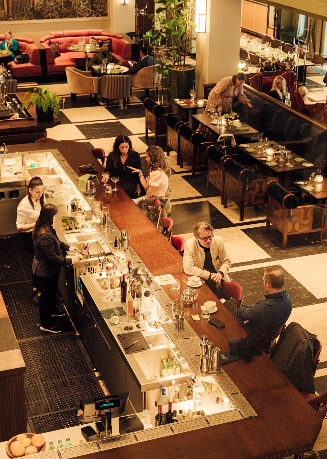 Overhead view of Sommerro hotel bar with guests seated at counter and bartenders serving drinks