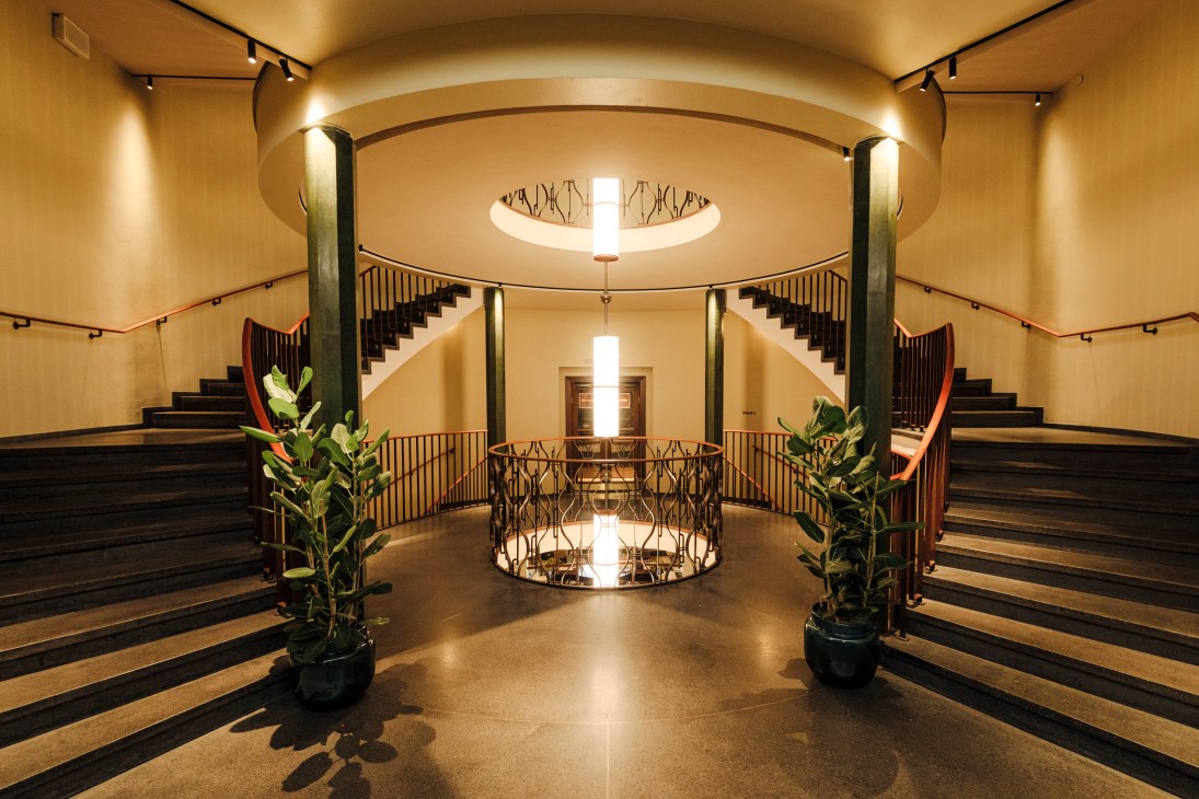 Grand circular staircase with art deco design featuring curved balustrades and warm lighting at Sommerro hotel