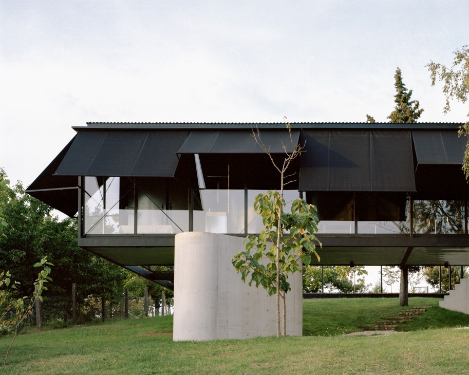 Avala House in Serbia with black metal and glass facade, solar panels on roof, set in landscaped grounds.