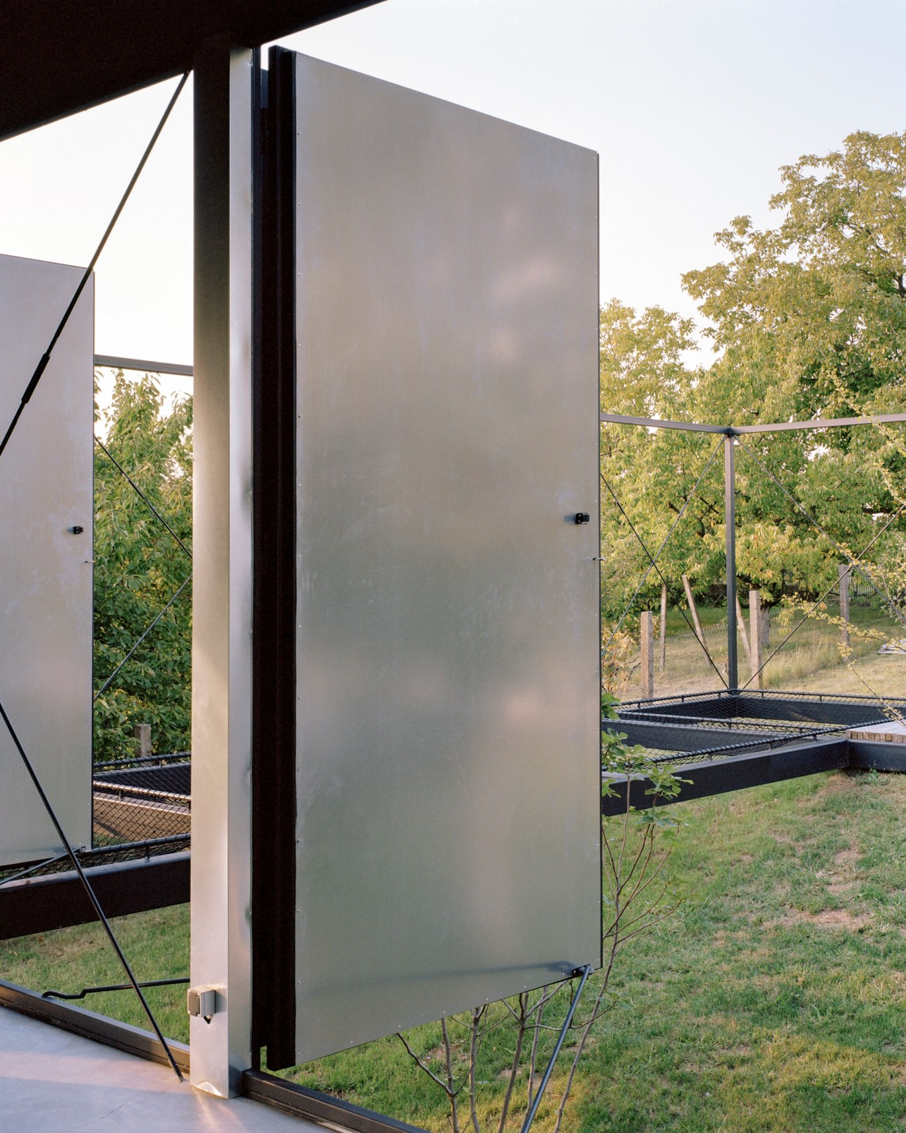 Avala House's large glass sliding door opens onto a landscape with vegetation and garden beds.