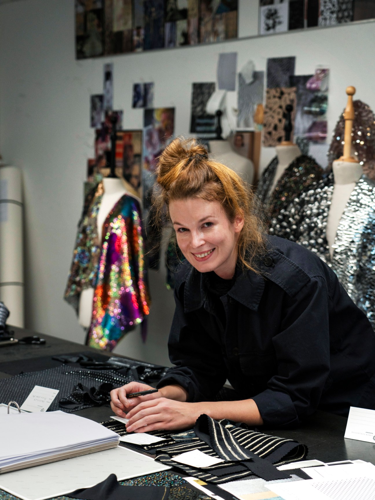 Designer working at desk with fabric samples and materials in textile design studio