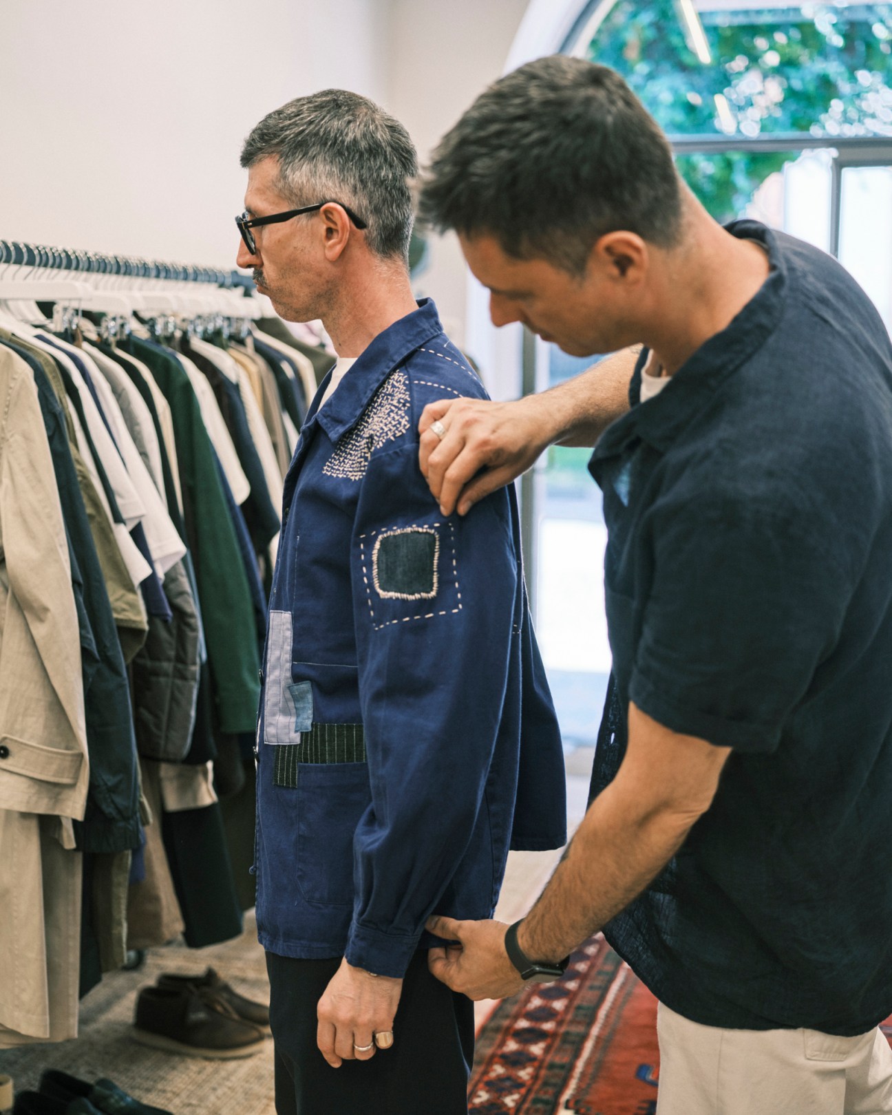 Shop assistant adjusting a blue jacket on a customer at Dictionary menswear store in Milan.