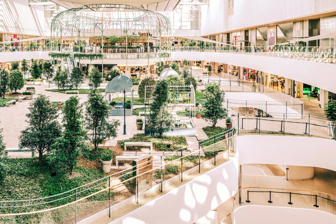 Interior view of The Hyundai Seoul shopping centre showing multiple levels with natural light, greenery, and modern architecture.