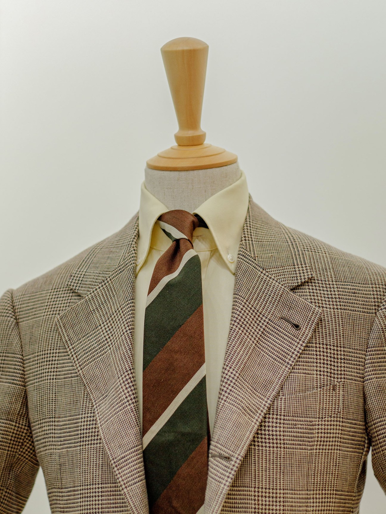 Man in grey glen plaid suit jacket with striped tie on dress form mannequin