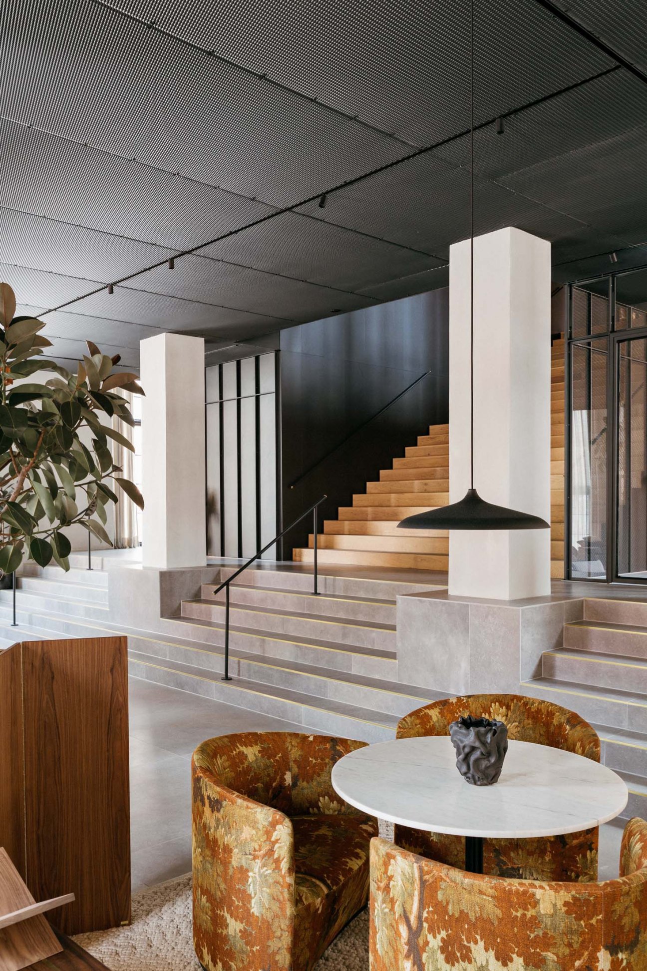 The Audo Copenhagen lobby featuring modern Scandinavian design with wooden stairs, marble table, and contemporary furniture.