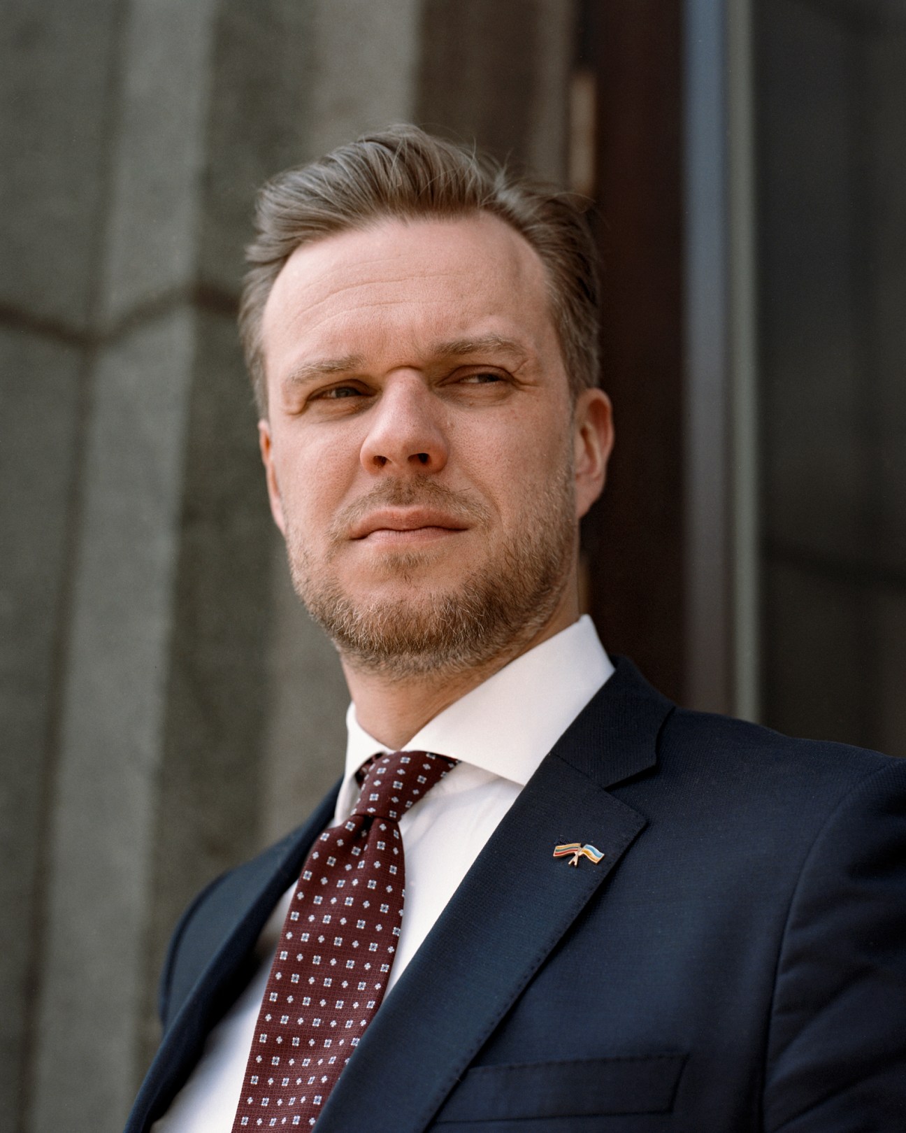 Man in dark suit and patterned tie standing outdoors in professional portrait