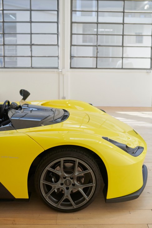 Bright yellow open-top sports car designed by Granstudio in a studio with large windows.