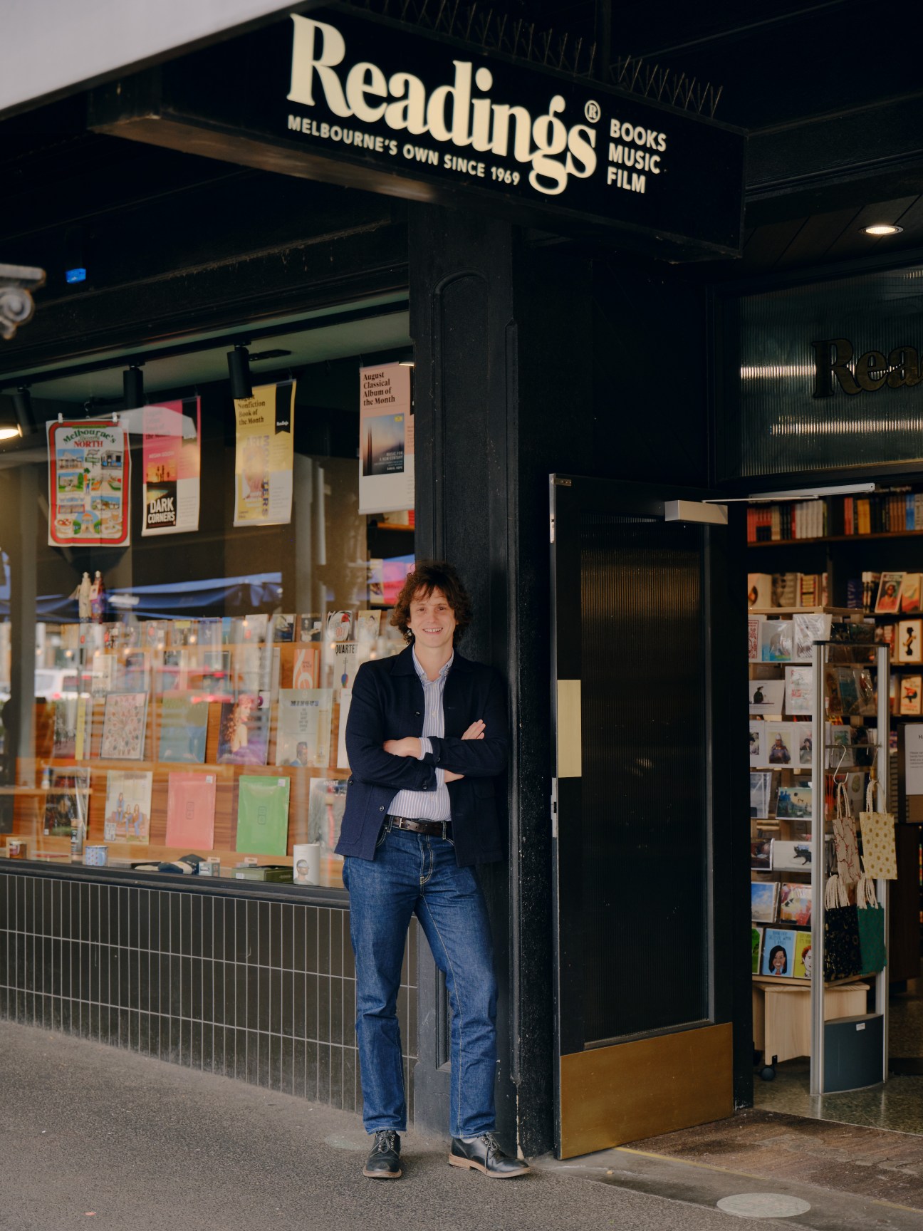 Joe Rubbo standing with arms crossed outside Readings bookstore in Melbourne