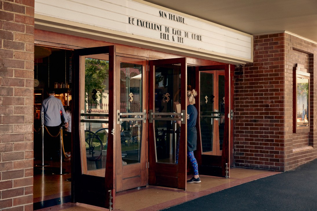 Art deco entrance of the Sun Theatre with glass doors and brick facade