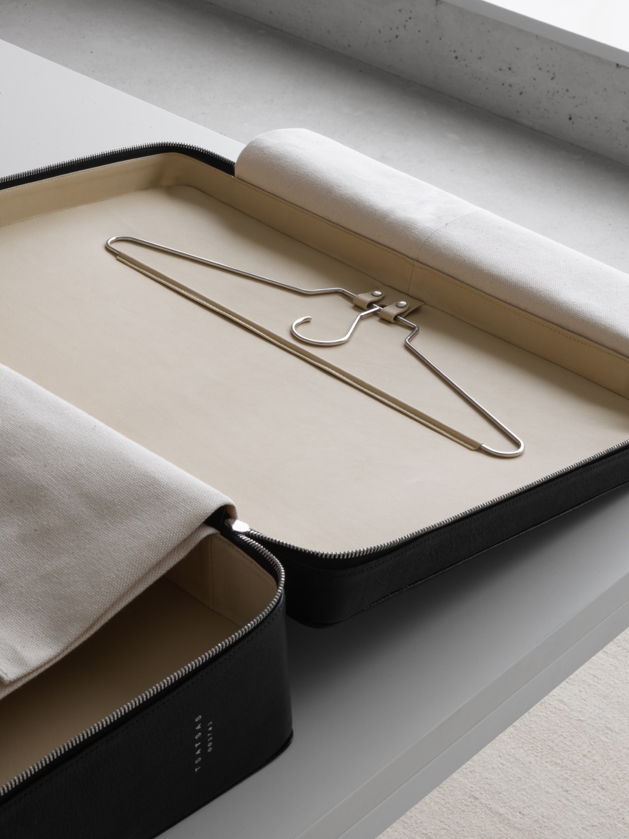 Tsatsas Suit-case interior showing wire coat hanger and cream fabric lining