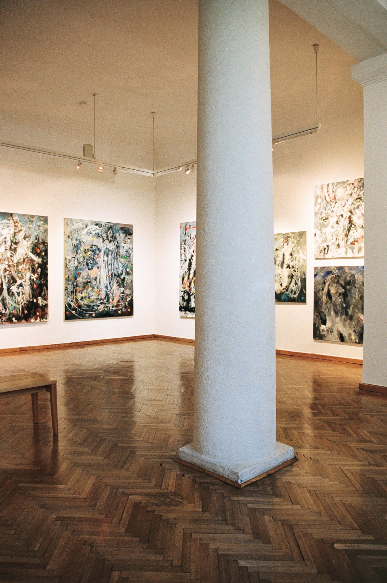 Interior of Maribor Art Gallery with paintings on white walls, parquet floors and white column