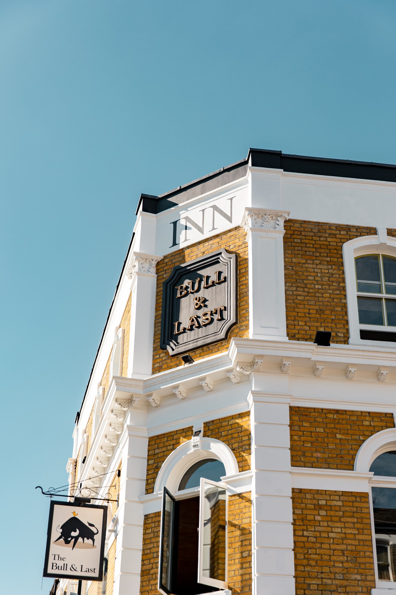 Victorian pub building exterior with yellow brick walls, white columns, and The Bull & Last signage