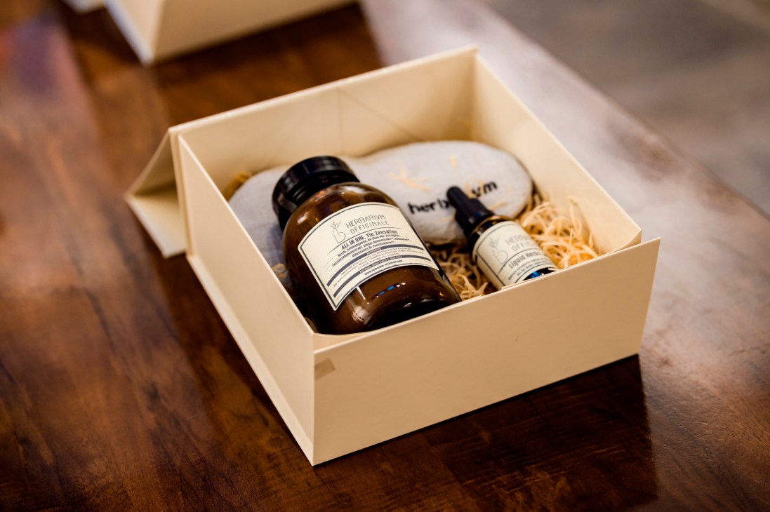 Gift box containing brown bottles and containers with herbal products and natural loofah sponge