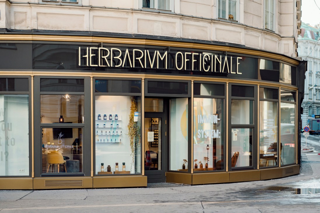 Exterior of Herbarium Officinale storefront with large windows and gold lettering on black facade