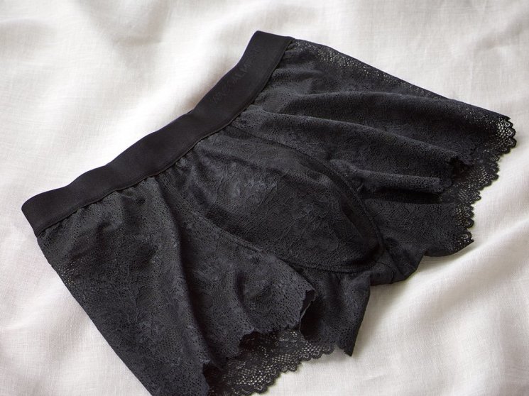 Black lace boxer underwear for men displayed on white fabric background