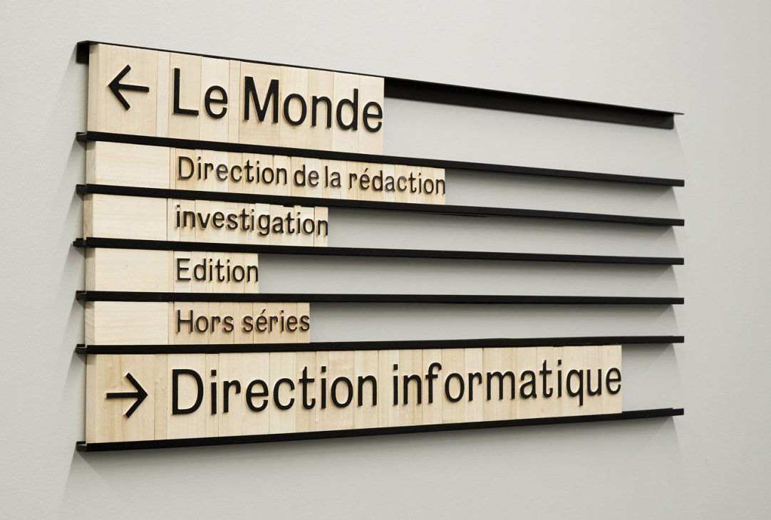 Snøhetta's modular wayfinding system at Le Monde Group headquarters showing wooden tiles with typography