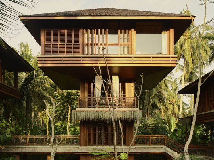 Multi-story wooden hotel building with slatted facades and balconies surrounded by lush tropical vegetation