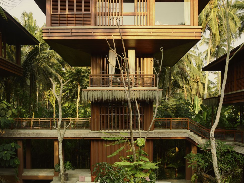 Multi-story wooden hotel building with slatted facades and balconies surrounded by lush tropical vegetation