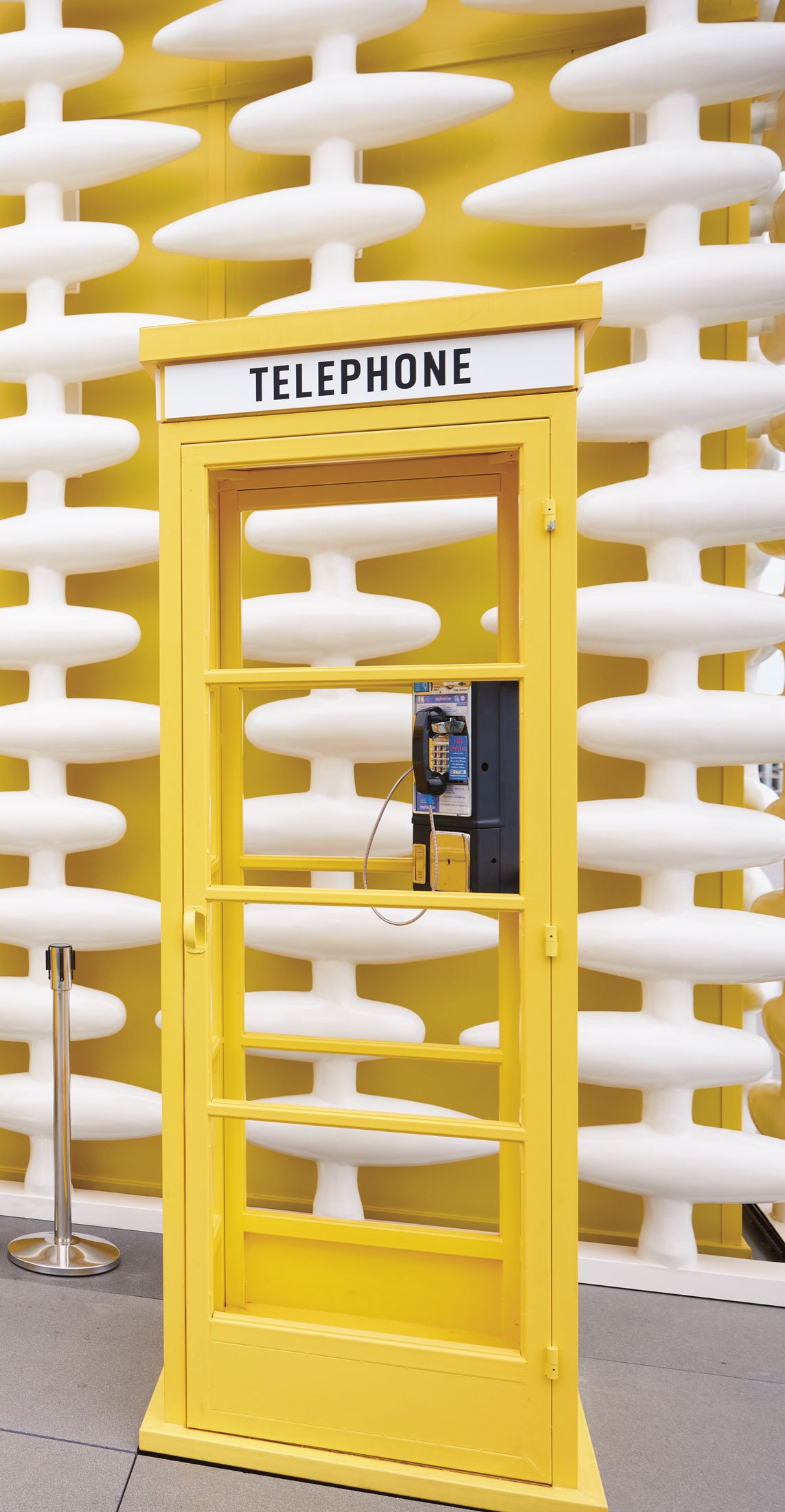 Yellow telephone booth at The Standard Bangkok with vintage rotary phone