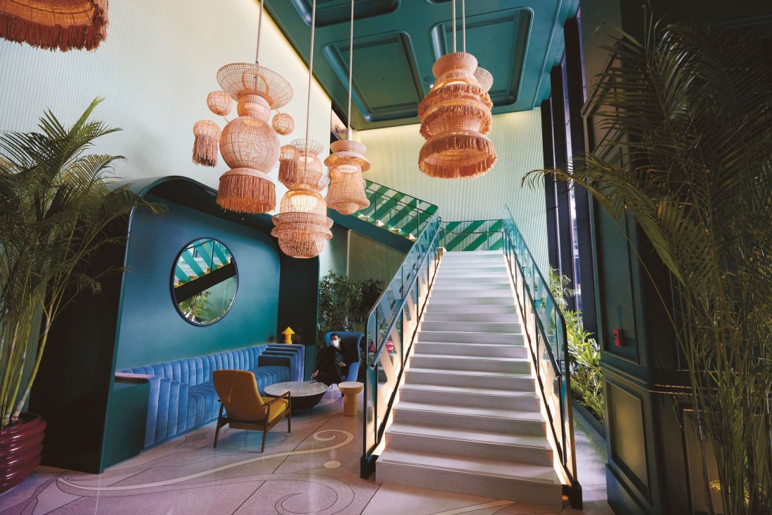Distinctive oversized woven lampshades hanging in a tropical-themed hotel lobby with blue seating and palm plants