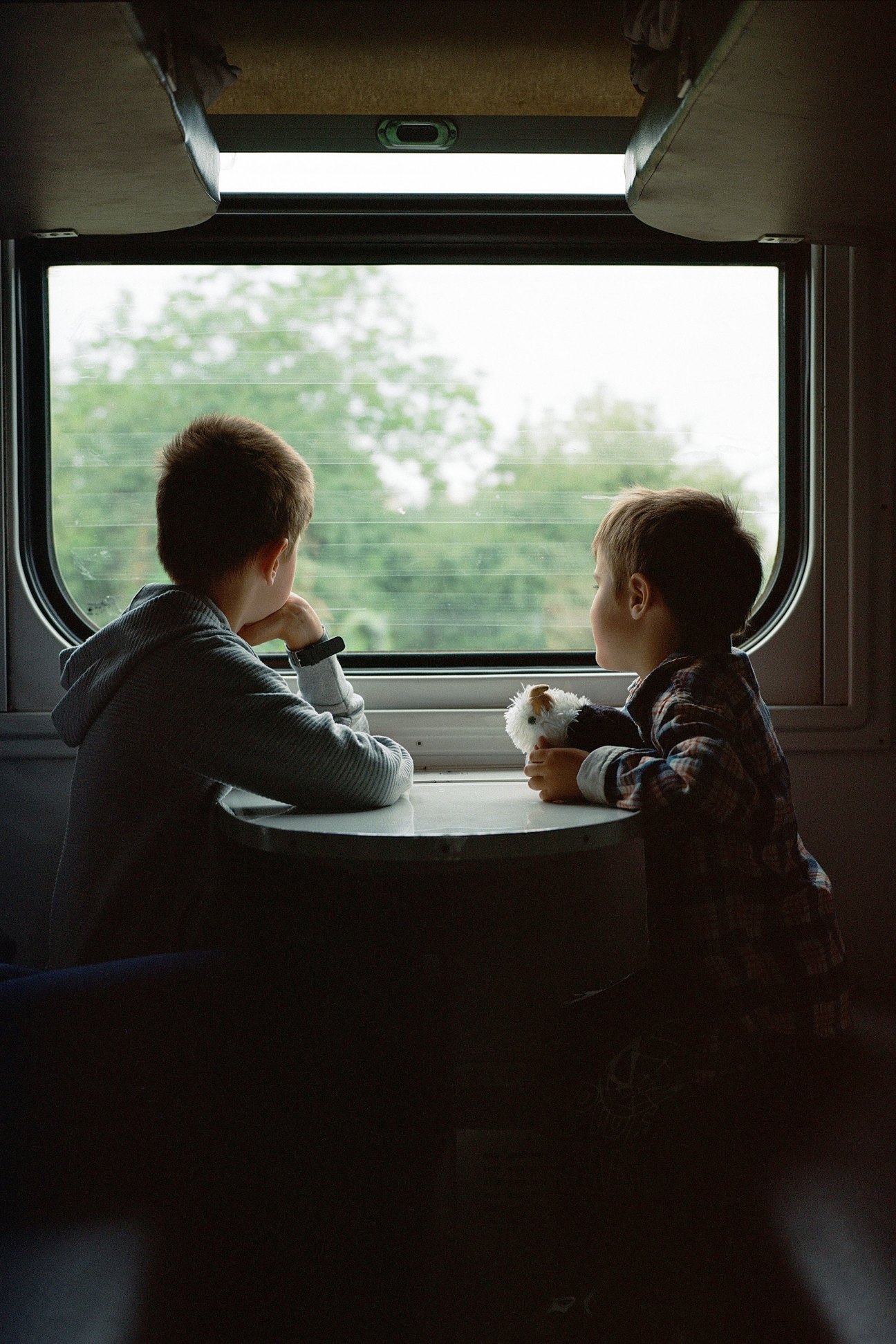 Two children looking out train window at Ukrainian countryside