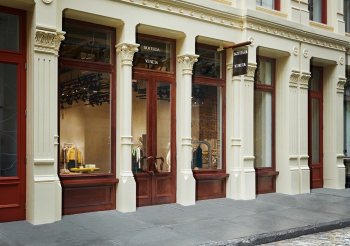 Bottega Veneta storefront in Soho featuring classical architecture with red doors, white columns, and large windows displaying merchandise.