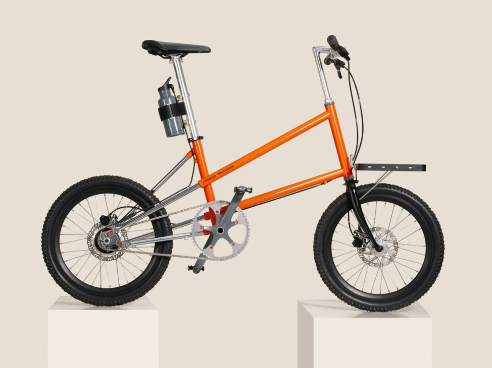 Orange Hermansen Bike One electric bicycle with sleek design and minimalist water bottle-style battery mounted on seat post