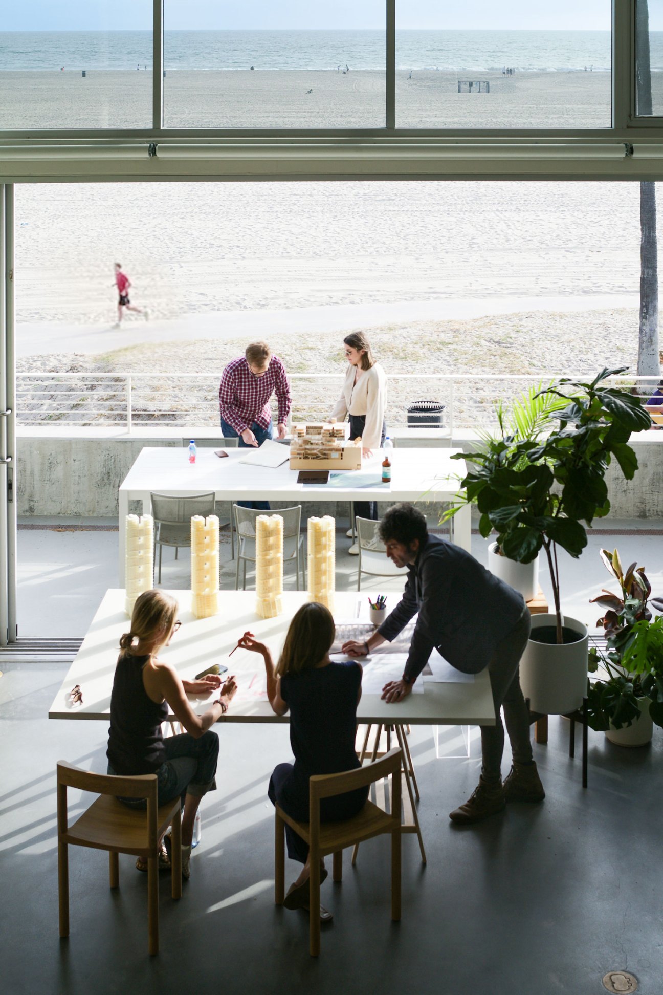 People working and collaborating in a modern office space with large windows overlooking a beach