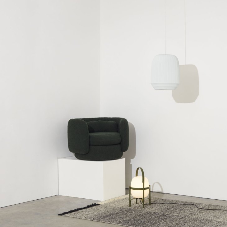 Dark green Group armchair on white cube with pendant light and floor lamp on patterned rug in corner