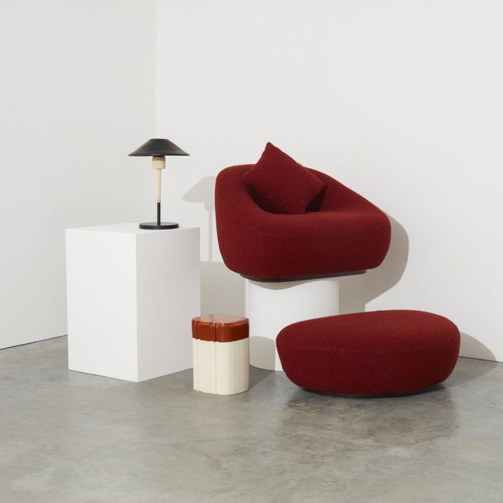 Raiz ceramic table lamp with cone shade next to red Sandia armchair and clay side table