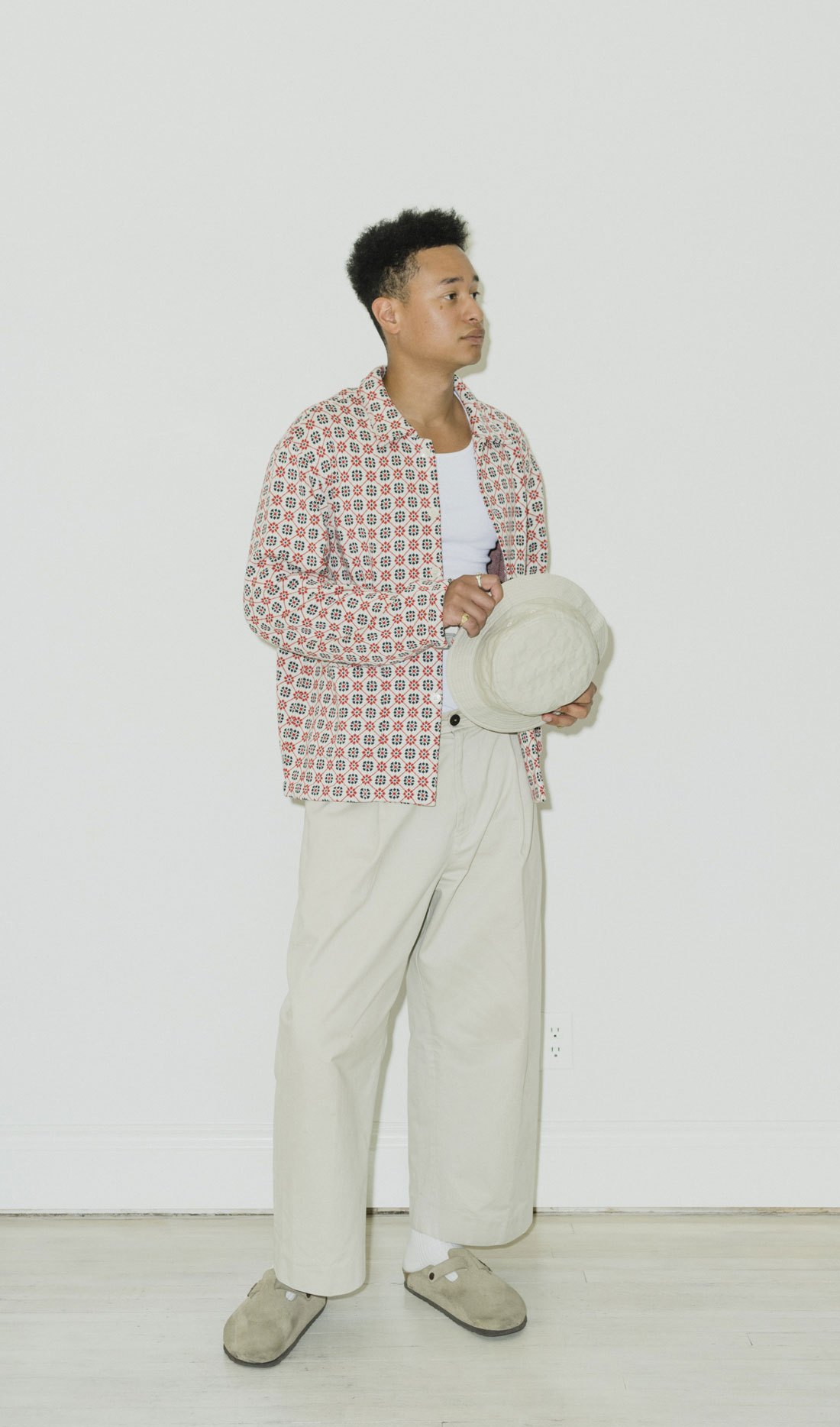Man in patterned shirt and light pants holding hat at Calculus menswear store in Victoria