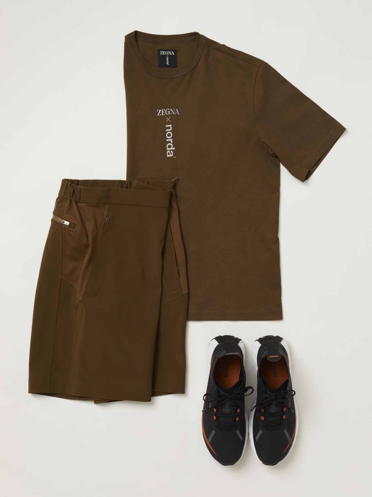 Olive green Zegna x Norda t-shirt, wrap shorts, and black technical sneakers arranged as a coordinated outfit